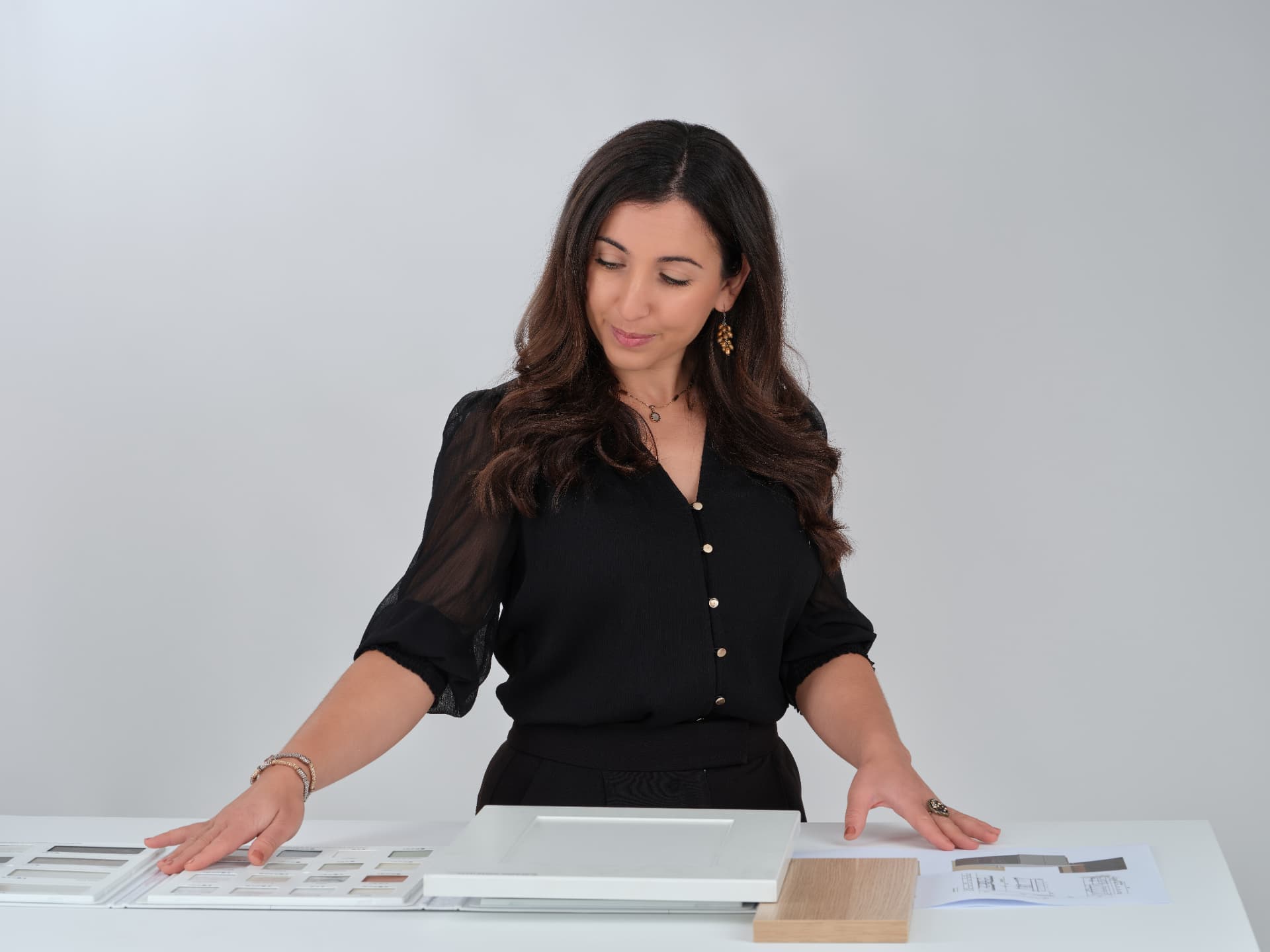 Belinda D'Angelo reviewing material samples and design sketches at her studio desk