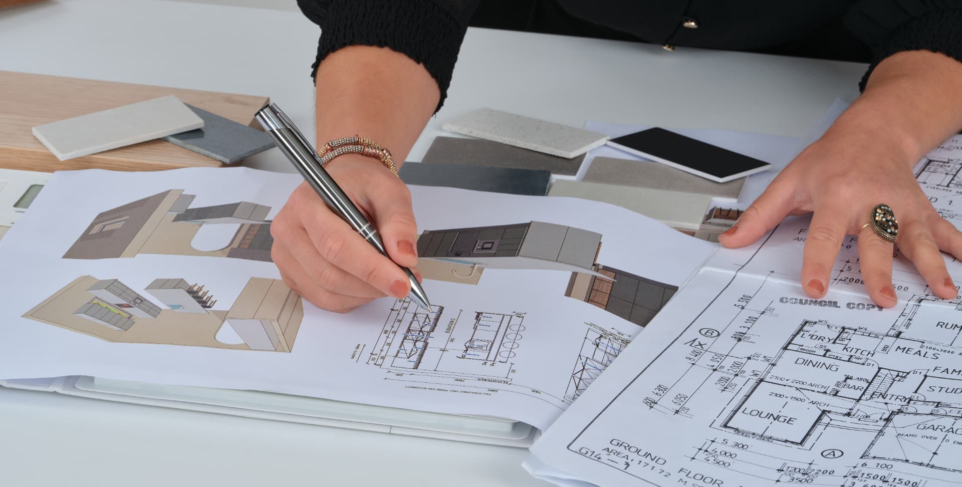 Floor plans and kitchen renderings with material samples and a designer's hands